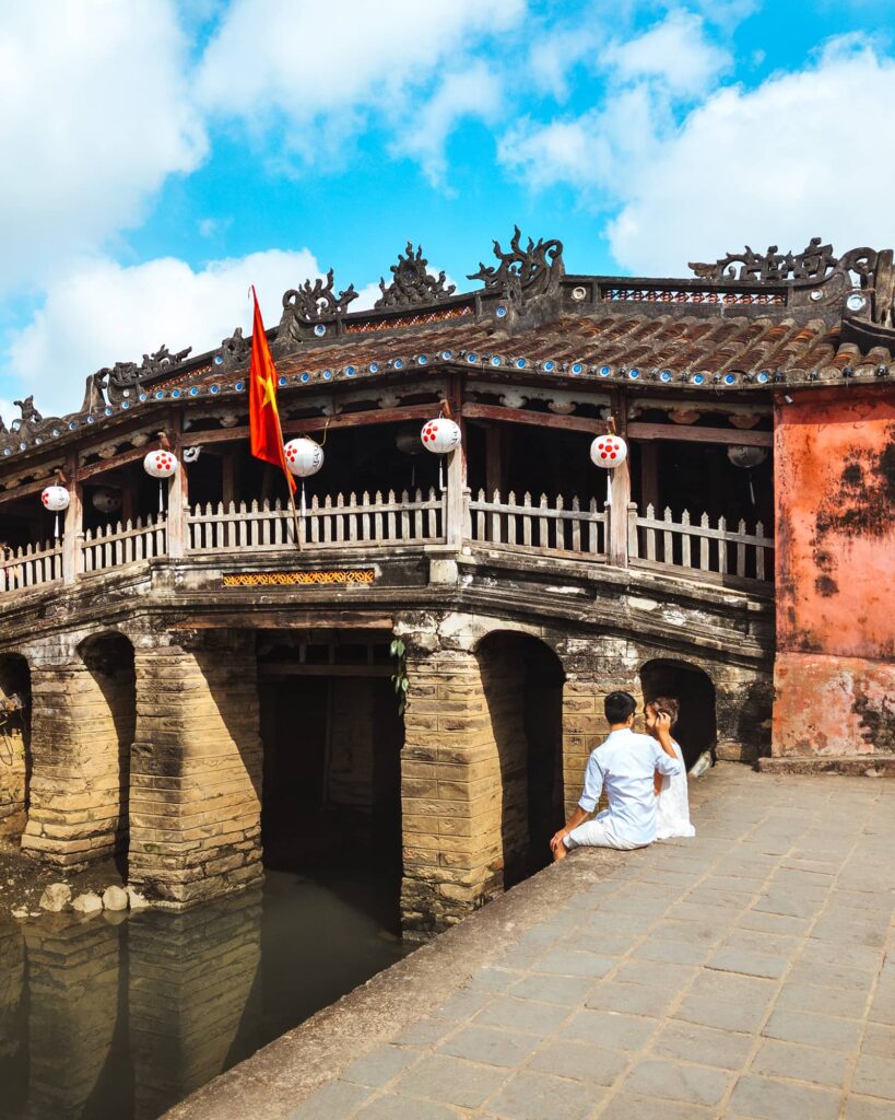 A couple sitting in front of the Japanese Bridge in Hoi An