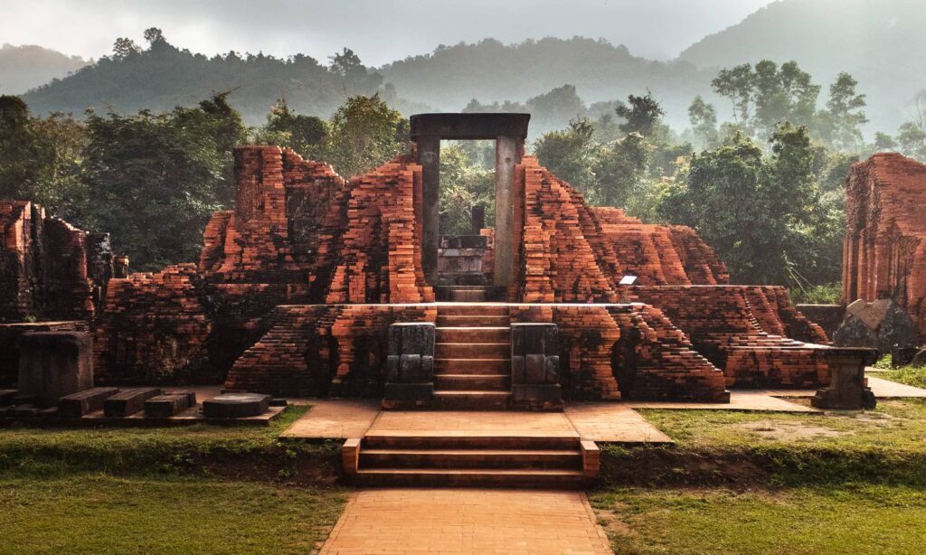 Steps leading up to the entrance of a temple in My Son Sanctuary with hills in the background
