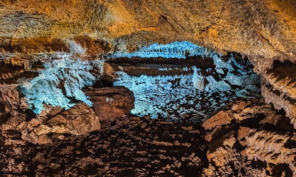 Cave tunnel entrance in Gruta do Carvao lit by blue light
