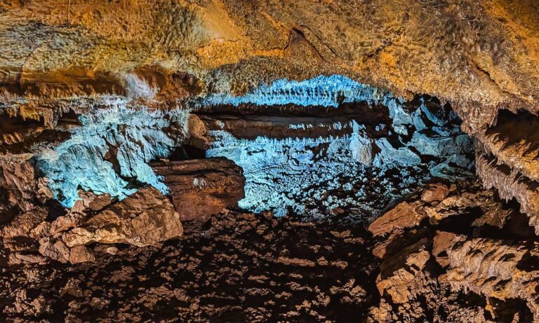 Cave tunnel entrance in Gruta do Carvao lit by blue light